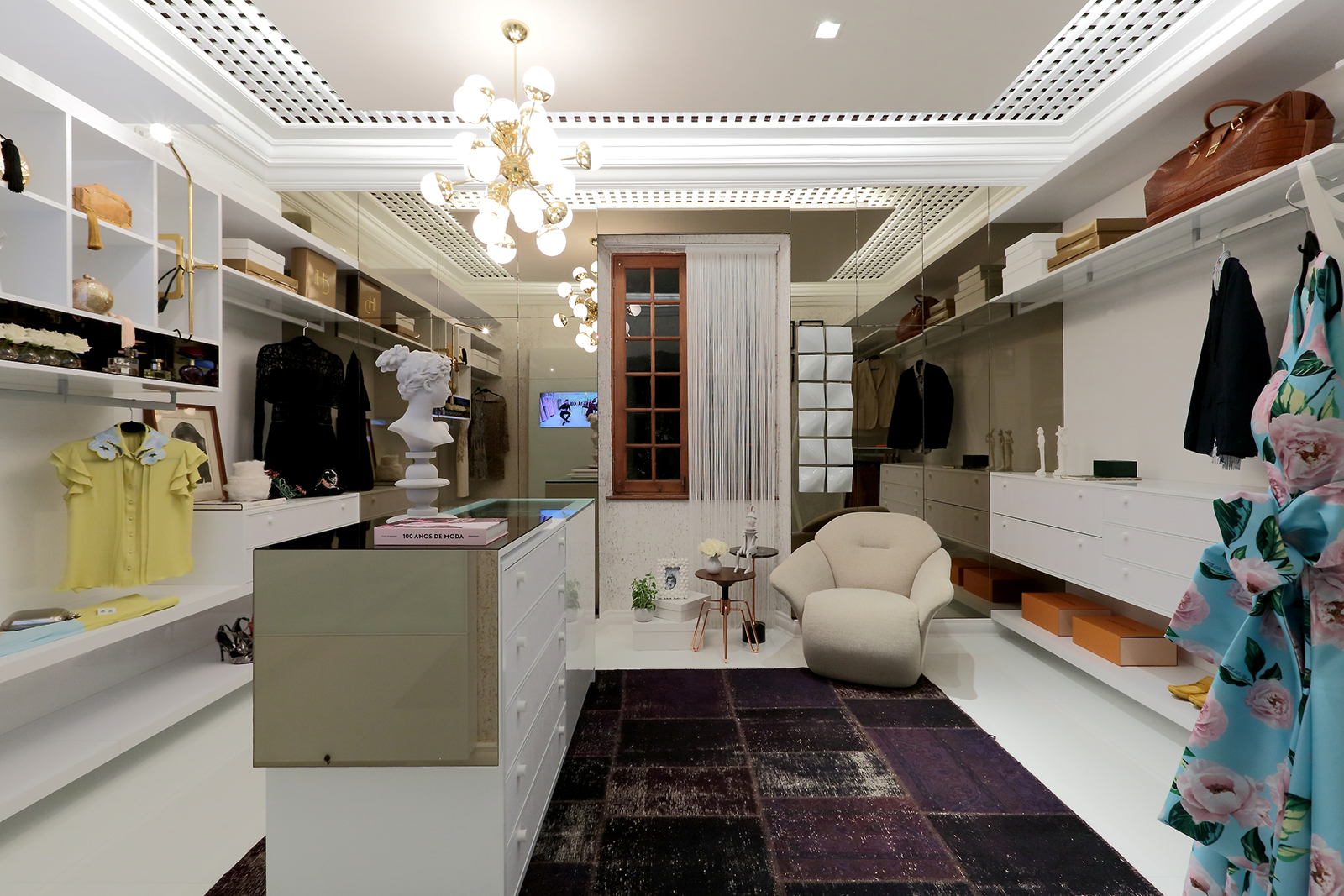 Closet com Sala de Estar - Sonia Beltrão, Gabriel Beltrão e Kátia Carapeba. A elegância discreta do branco define o espaço. Esse ambiente minimalista usa papeis de parede e um tapete iraniano envelhecido para completar sua proposta de forma equilibrada.