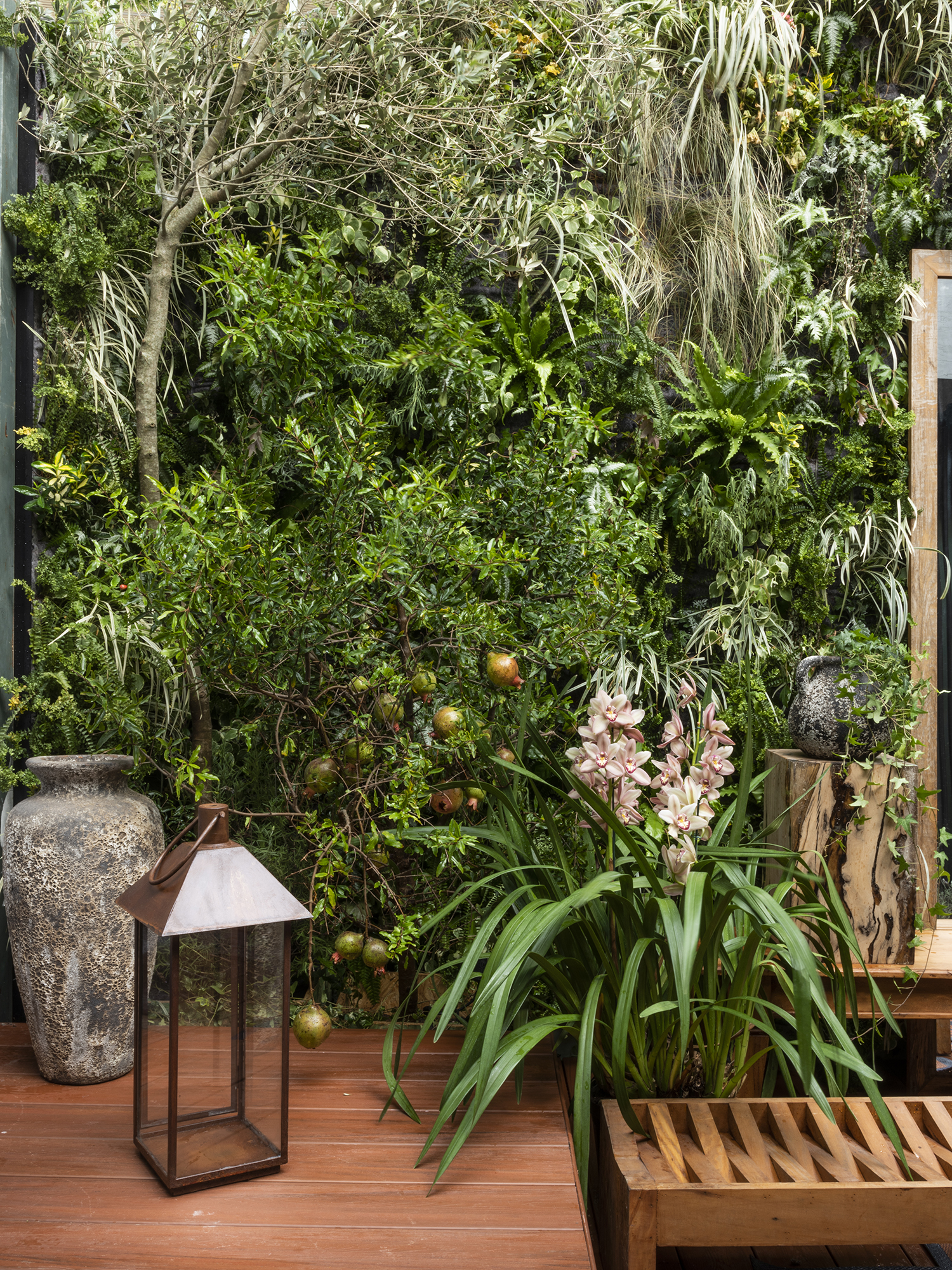 Jardim do Entardecer - Myrian Marquez. Oliveiras e romãzeiras em vasos, entre outras plantas, criam uma atmosfera onírica que celebra o feminino. Mais precisamente, as ninfas gregas Hespérides, que personificam o entardecer. O banco de madeira ecológica convida a apreciar a paisagem.