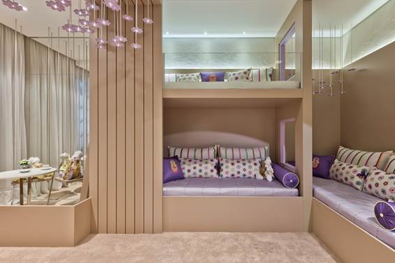 Quarto de Gêmeas –Mariana Stockler e Carolina Posanske. A decoração infantil dé pautada em MDF bege e tons de lilás criando um ambiente leve, lúdico e feminino. Destaque para o teto em madeira, onde floresce um delicado jardim suspenso.