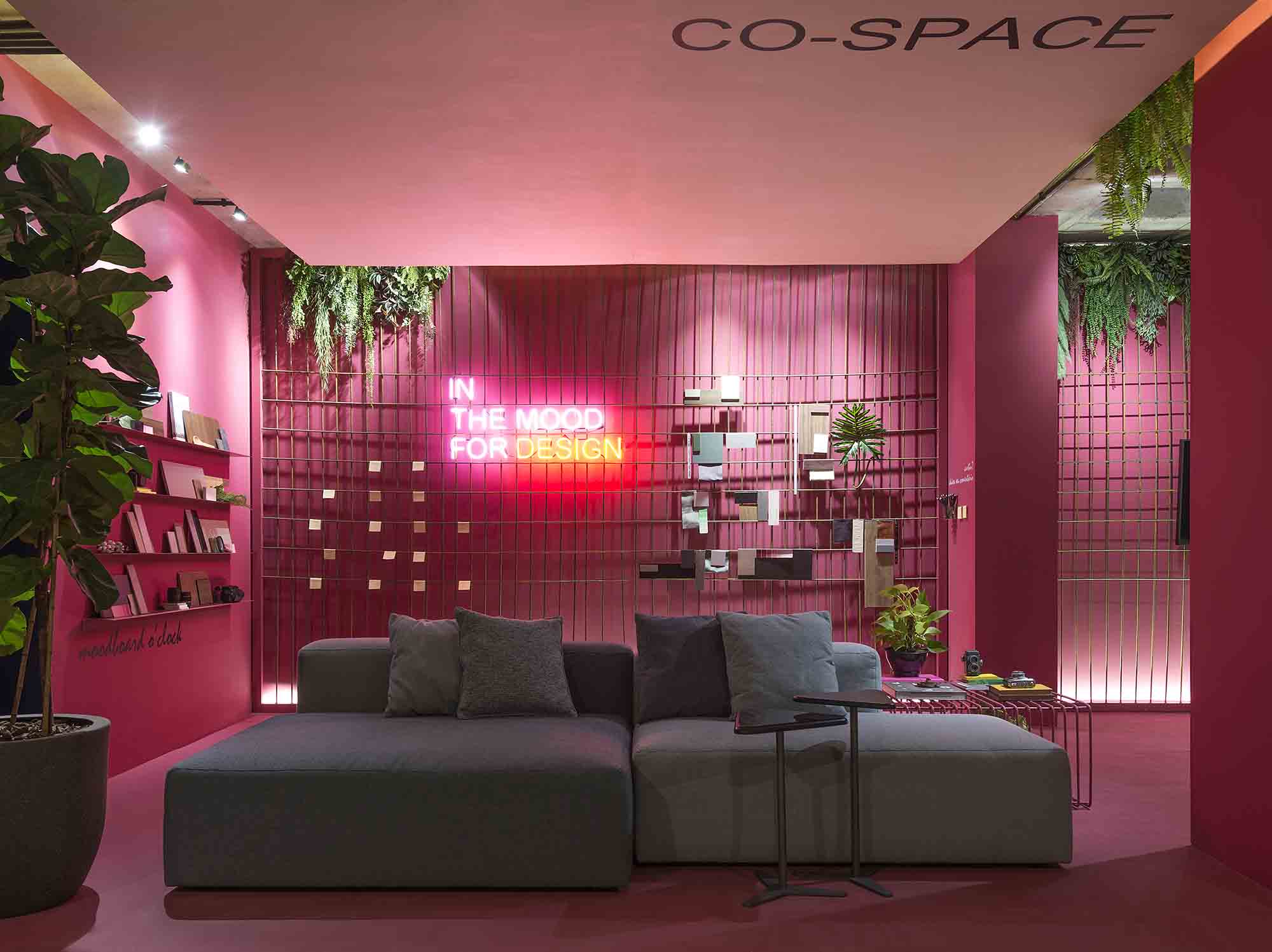 Co-Space para Arquitetos e Designers - Barbara Ramos e Maria Eduarda Brandão. O ambiente de trabalho e reuniões informais também atende aos momentos de descompressão. Instagramável, a caixa que envolve todo o espaço e cria unidade visual foi tingida de pink. O perfeito contrapondo é a cor verde, inserida por meio dos ficus, samambaias e jibóias que dão vida ao lugar. O sofá modular torna o ambiente versátil, na mesma pegada das prateleiras e da tela metálica que deixam as paredes mais funcionais.