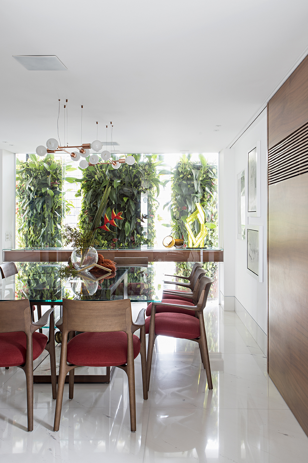 Apartamento nos Jardins - São Paulo. Além da mudança de layout, este imóvel de 350 m² ganhou personalidade nas mãos do Korman Arquitetos: um espelho no hall supreende os visitantes, assim como a cadeira do século XVII. Nos interiores, peças de design internacional se intercalam com peças de antiquário do acervo pessoal da moradora, obras de arte e o jardim vertical emoldura o jantar.