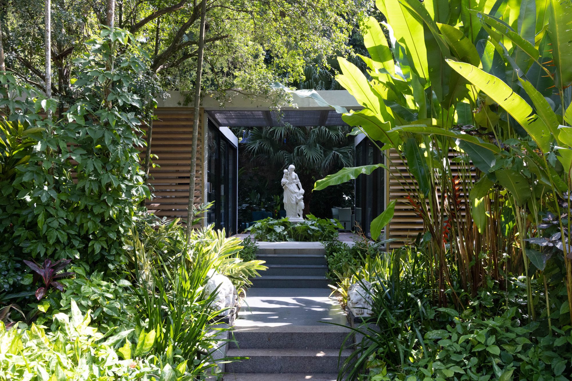 Ana Veras - Jardim do Pavilhão 22. Ao lado da piscina, a mata se torna ainda mais exuberante e colorida com a interferência paisagística. O local, onde aflora uma nascente, teve o caminho para o olho d’água aberto, convidando o visitante a viver essa experiência sensorial. Novas espécies, que atraem a fauna local (beija-flores, tucanos, saguis), foram incorporadas criando um jardim tropical de formas livres que abraça o Pavilhão 22 e traz em sua entrada duas esculturas vivas de bromélias, uma releitura dos totens de Burle Marx.