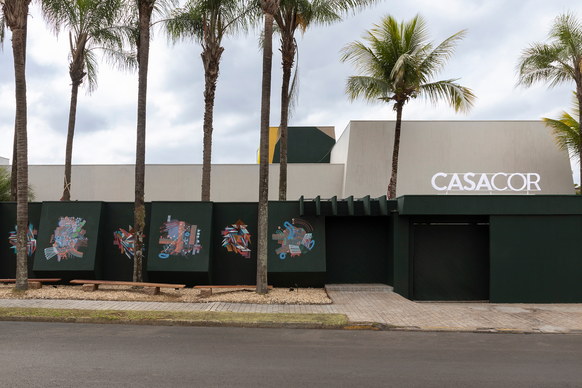 A7MA Galeria - Fachada - Corpo Casa Corpo Cor (Arte Visual). A CASACOR Ribeirão Preto 2023 dá as boas-vindas com cores, formas abstratas e muito movimento. A intervenção nas fachadas frontal e posterior tem a assinatura de Tché Ruggi e Luís Alexandre Lobot, que fazem da arte urbana uma das atrações da mostra. Na originalidade dos traços estão presentes as técnicas do grafite e do muralismo, complementadas por elementos como as chapas de aço e a madeira que compõe as esculturas. “Nesse encontro da street art com o contemporâneo, propomos a conexão do universo mineral com a imensidão das moléculas e corpos celestes que habitam o nosso imaginário”. Assim a obra é definida por Tché e Lobot, ambos da A7MA Galeria, que tem como endereço o Beco do Batman (na Vila Madalena), referência da arte urbana paulistana. “A inspiração veio da vontade de transformar o mundo em um lugar mais alegre, colorido e atualizado.”