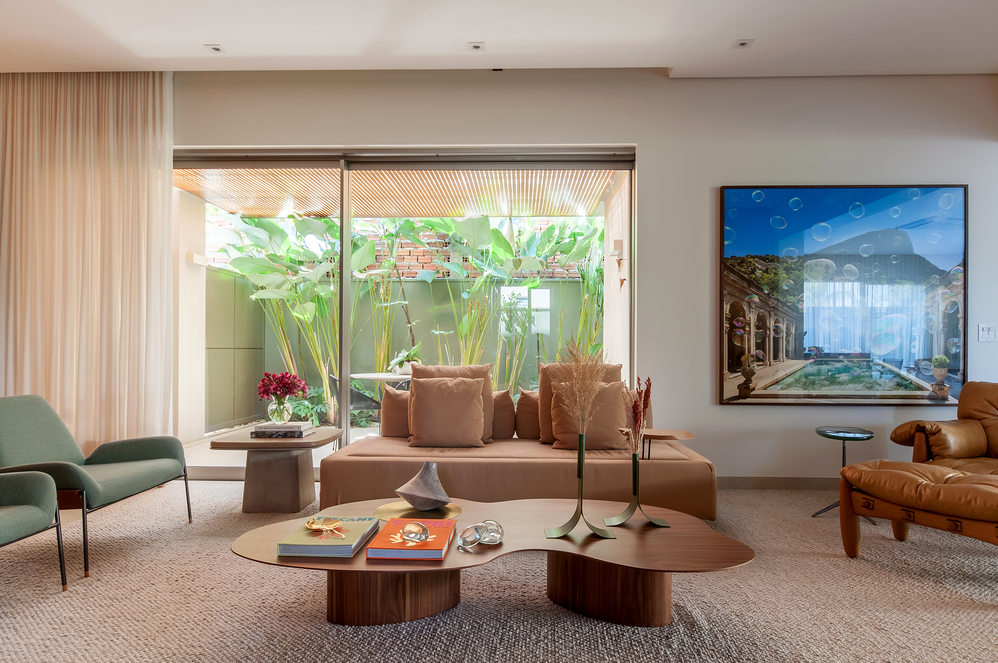 Construída do zero, casa une ambientes integrados e design nacional. Projeto de Paiva e Passarini Arquitetura. Na foto, sala de estar com painel de madeira e quadros.