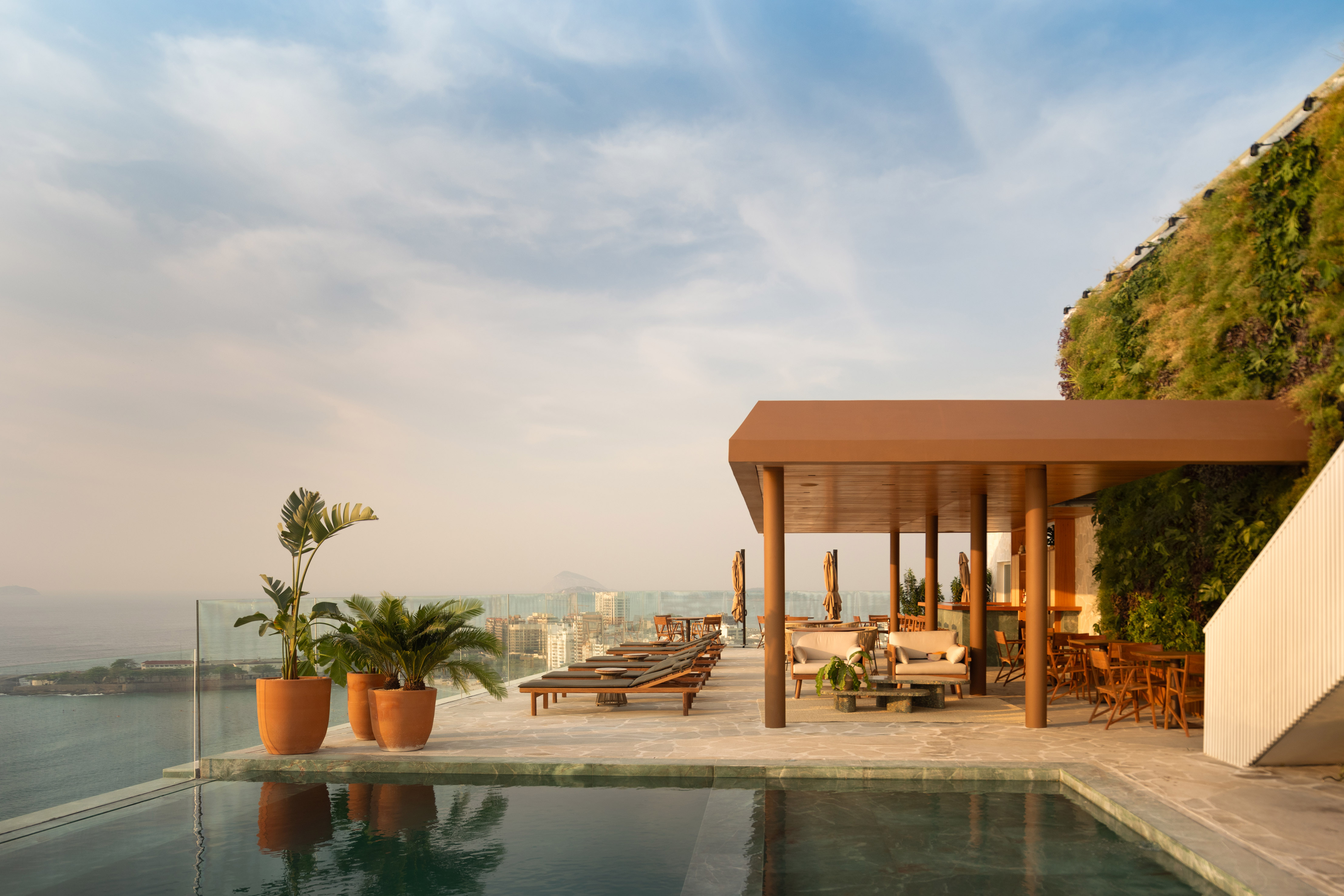 Novo rooftop do Rio Othon Palace traz a piscina mais alta de Copacabana. Projeto de PKB Arquitetura. Na foto, restaurante com área externa e espreguiçadeiras. Piscina de borda infinita.